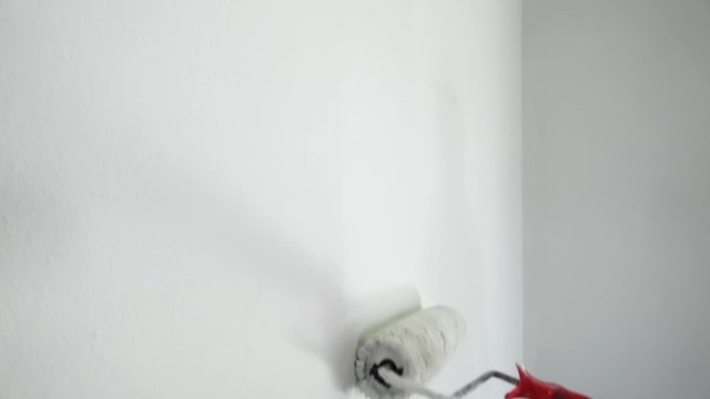 Farbroller mit wei&szlig;er Farbe malt eine Wand zu Hause