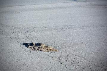 A large pit on the road made of asphalt. Broken road. The concept is dangerous to drive a car on a road without repair