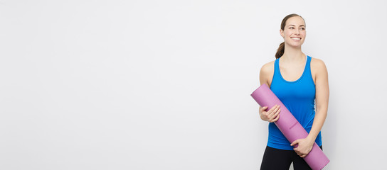 Sporty woman concept, stading with her yoga mat on a plain backdrop  
