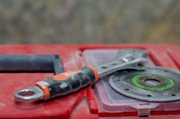 The circle for the grinder and the adjustable wrench are on the red tool box. Worker preparing for repair in the apartment.