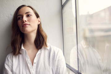 portrait of thoughtful pretty woman sitting in a window 