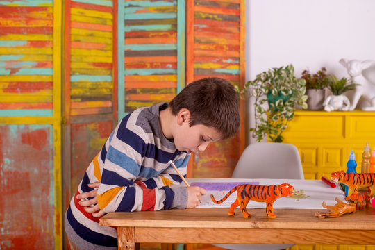 Boy drawing at table, indoors.