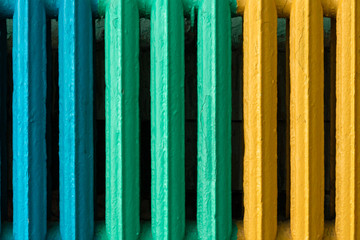 Vintage and hipster heating radiator made from cast iron close-up. Blue, green and yellow color convector as a background for copy space