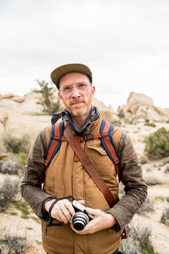 Focused mature man with camera and backpack in desert