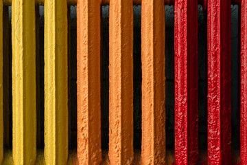 Vintage and hipster heating radiator made from cast iron close-up. Yellow, orange and red color convector as a background for copy space