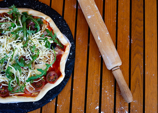Vegetarian and vegetable pizza next to a wooden rolling pin.
