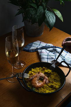 a plate of Spanish paella prepared for two accompanied by two glasses