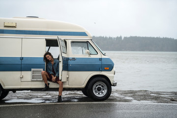 Teenage girl getting into vintage van on rainy day