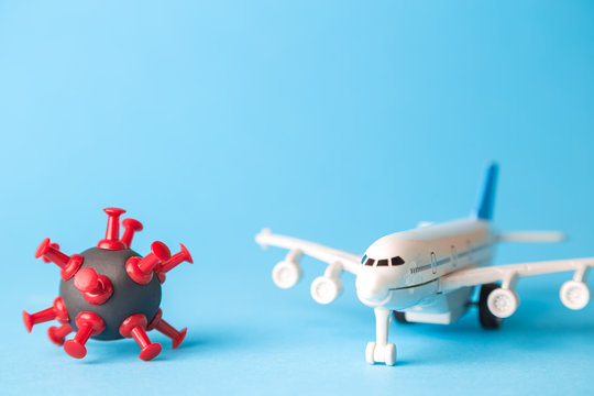 Travel restrictions concept made of coronavirus cell and airplane toy on pastel blue background.