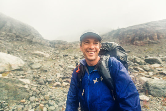 Backpacker smiling despite bad weather, rain and wind.