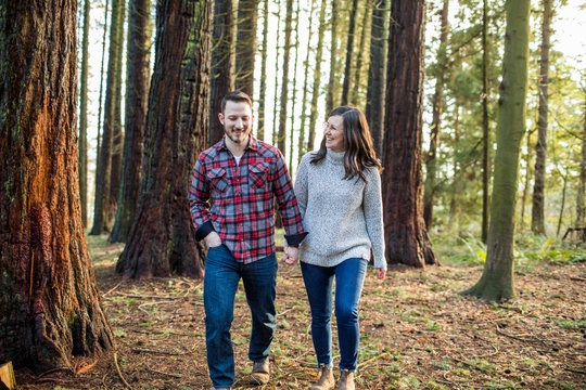 Relaxed couple walking through forest in evening light.