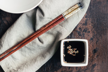 Soy sauce and sesame in a vessel and bamboo chopsticks
