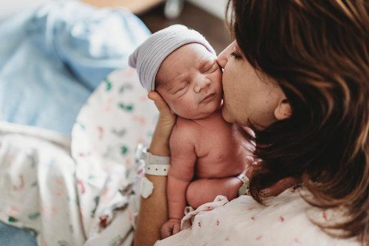Close up of mother kissing newborn son's cheek in hospital