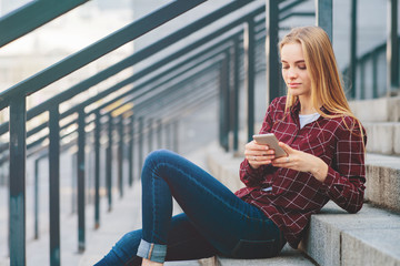 The girl is sitting on the steps and talking on the phone