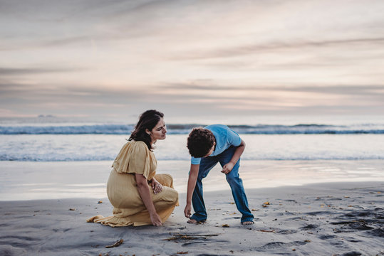 Lifestyle of young mother and school-aged son looking for seashells