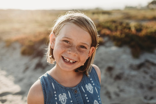 Portrait of young school age girl with freckles smiling on beach