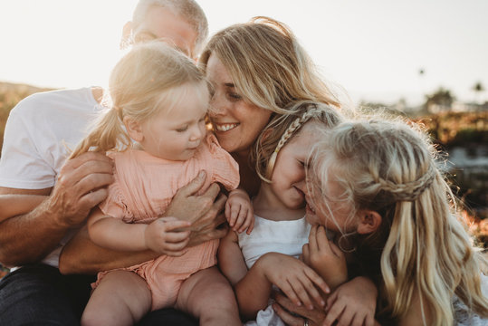 Lifestyle close up of family with young sisters sitting on beach