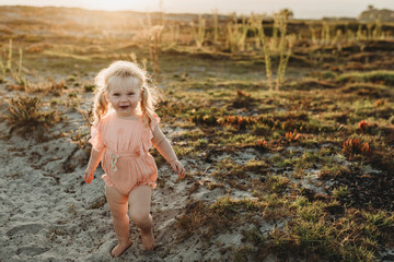 Portrait of toddler girl with pigtails smiling at camera at beach