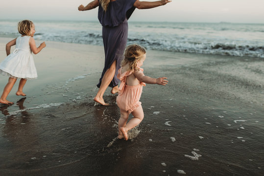 Behind view of young family walking towards the ocean at sunset
