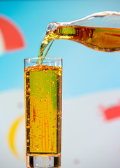Pear carbonated drink pours from a bottle into a glass