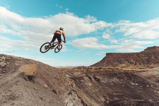 Male jumping with mountain bike in front of dramatic mountains