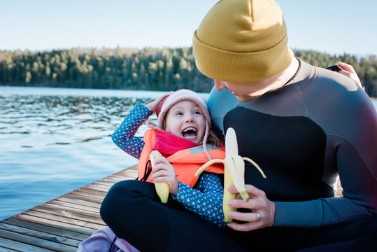 father and daughter eating fruit laughing at the beach on vacation