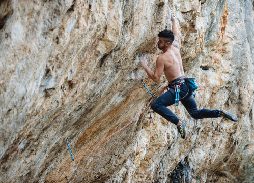 Shirtless climber sending a sport climbing route on spanish crag.