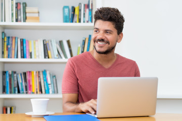 Attractive latin american man with beard working at computer
