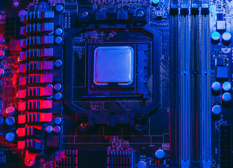 Hardware technology concept in neon light. Motherboard in blue-red light. Computer accessories. Dark photo..