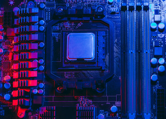 Fototapeta premium Hardware technology concept in neon light. Motherboard in blue-red light. Computer accessories. Dark photo..