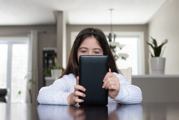 Child  at home playing educational apps on her electronic tablet