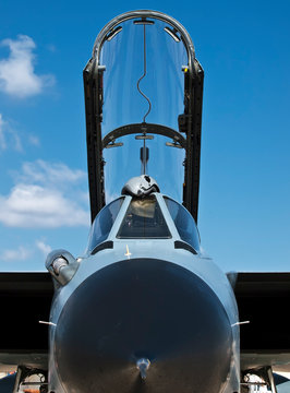 Military fighter jet with open canopy against blue sky
