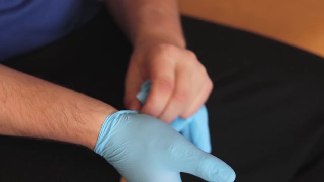 Extreme Close Up Shot Of A Man's Hands Taking Off Surgical Latex Gloves Protecting From Bacteria And Viruses.