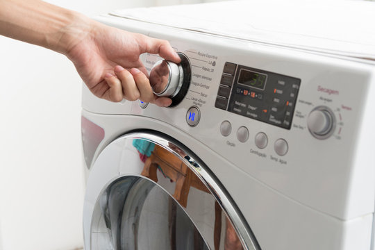 Male hand operating a washing machine at home