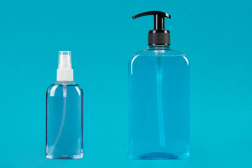 Sanitizer dispenser and liquid soap bottle on blue background