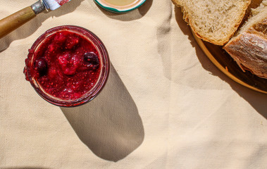 Homemade strawberry and blueberry jam in glass jar with rustic bread. Homemade rustic and natural breakfast table. Top View and space for text. 