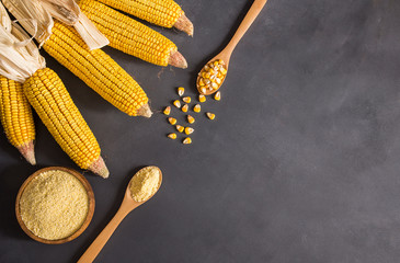 Corn flour in wooden bowl and spoon with dried corn groats, kernels on rustic table. corn ingredients concept