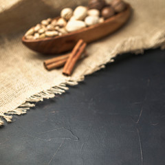 nuts in a wooden bowl shaped like a boat on a dark concrete background and burlap