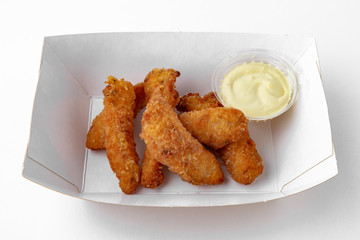 Sliced chicken in crispy batter with sauce in a paper plate for take away or food delivery isolated on a white background.