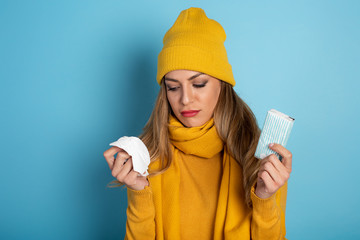 Girl caught a cold and wipes her nose. Cyan background