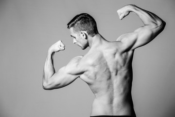 Close up image of a male fitness model flexing his body in a studio