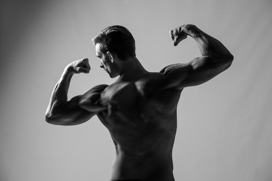 Close up image of a male fitness model flexing his body in a studio