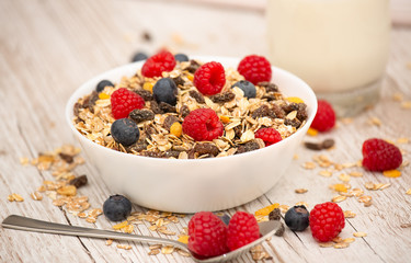 Breakfast Served in the morning with corn flakes Whole grains and raisins with milk in cups and Strawberry, Blueberry, Raspberry, Kiwi on the wood table,Diet food or healthy food in the morning.