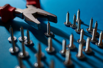 Screws and pliers on a blue background.