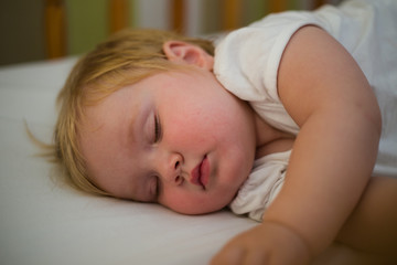 Close up image of a toddler girl sleeping in a cot