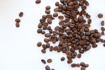 Coffee beans scattered on a white background, top view.