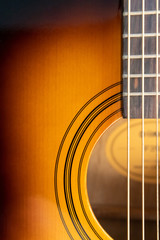 Sound hole of an acoustic guitar, neck, strings, frets, the nut.