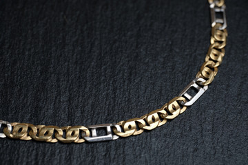 Fototapeta na wymiar Gold and white chain on a stone board.