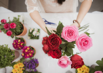 Woman Preparing to trim red and pink roses and beautiful flower arrangements in the home, flower arrangements with vase for gift-giving for Valentine's Day and Business in the family on the on table