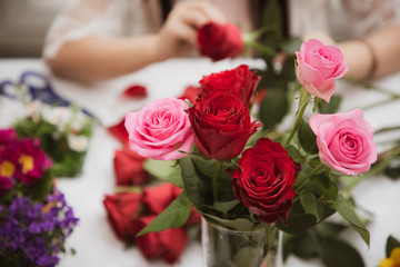 Woman Preparing to trim red and pink roses and beautiful flower arrangements in the home, flower arrangements with vase for gift-giving for Valentine's Day and Business in the family on the on table
